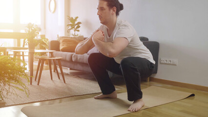 Workout at home concept. Young male doing squat