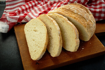 Fresh slice of bread on wooden cutting board on the black background.