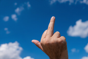 hand shows the middle finger on the background of the sky