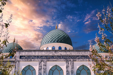 blue dome of Ahror Valiy mosque on background of flowering trees and a beautiful sky in spring in...