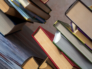 Stacks of books on the table at an angle to the background. Close-up. Books lie on top of each...