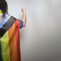 lgbtq+ pride 2024 protest concept. Male raises fists by new lgbt flag over gray background with copy space