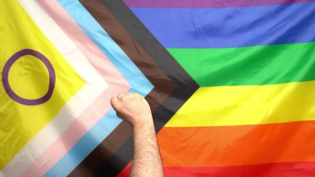 lgbtq+ pride 2024 protest concept. Fist raised by new lgbt flag