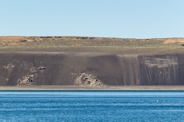 a unique panoramic view over the mono Lake to an steep dark sandstone cliff, california