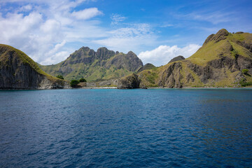 Majestic mountain peaks tower over the serene blue waters near Komodo Island, a gem in Indonesia's archipelago