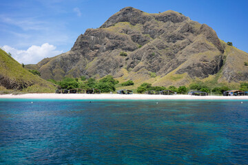Crystal clear turquoise waters meet a secluded pink sand beach under the towering hills of Komodo...