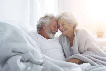 Handsome old man and attractive old woman are enjoying spending time together while lying in bed. Senior couple embracing and cuddling lying in bed and falling asleep in evening, St Valentine day