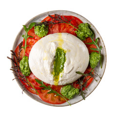 Tomato salad with burrata cheese and green pesto on gray plate isolated on white background. Top view.