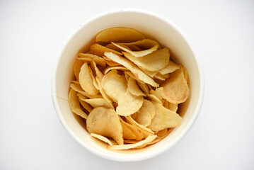 Delicious salted potato chips in a cardboard jar on a white background. Fast food.