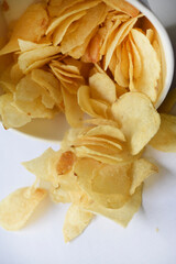 Delicious salted potato chips in a cardboard jar on a white background. Fast food.