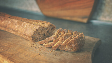 A baguette of sliced ​​buckwheat dark bread on a wooden cutting board. Closeup - obrazy, fototapety, plakaty