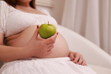 Indulging in a wide range of fresh fruits and vegetables, a healthy, pregnant Asian woman sits back...