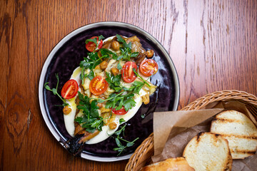 Salad with cherry tomatoes and herbs top view on a black plate