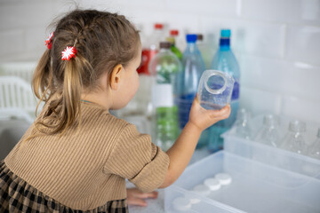 The daughter, under the supervision of her mother, helps sort plastic bottles for recycling. Cute...