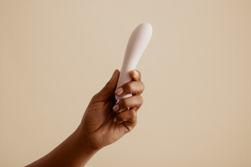 Female hand holds lubricated vibrator for solo pleasure