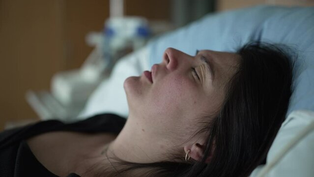Suffering pregnant woman laid at hospital bed feeling contractions, close-up face of female patient with eyes closed struggles with pain during prelabor
