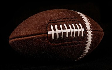 Brown American football with white laces, textured surface.