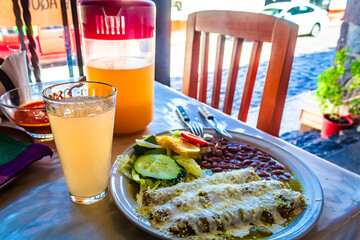 Mexican food, green enchiladas with beans accompanied by water, Mexican fonda food