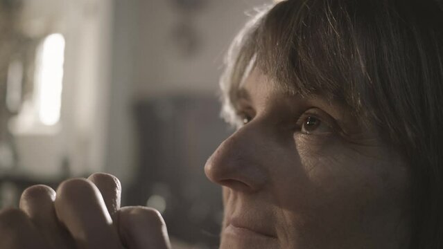 Christian religious woman praying with clasped hands close up. Faith and hope concept. Caucasian mid adult parishioner looking upwards during prayer in church