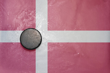 old hockey puck is on the ice with national flag of denmark .