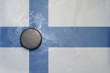 Naklejka premium old hockey puck is on the ice with national flag of finland .