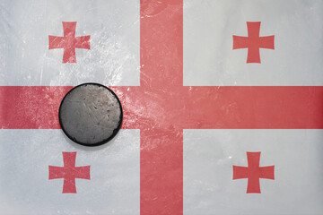 old hockey puck is on the ice with national flag of georgia .