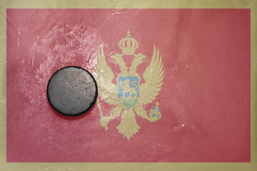 old hockey puck is on the ice with national flag of montenegro .