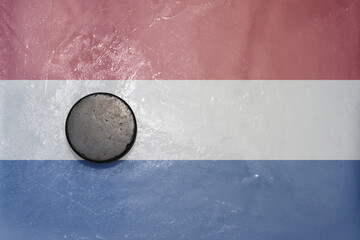 old hockey puck is on the ice with national flag of netherlands .