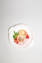 Top view of delicious cottage cheese pancakes with berries on a plate on a white background