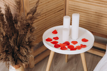 Bedroom and kitchen with many red flowers rose petals and candles in hotel room apartment....
