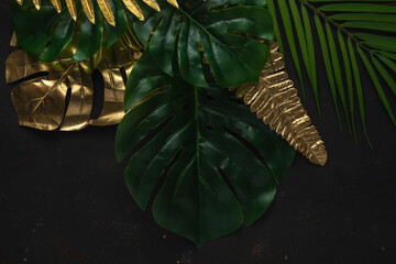 Creative layout with gold and green tropical palm leaves on black background. Minimal summer...