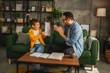 Happy and satisfied little boy show his father good grade on his test