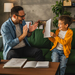 Happy and satisfied little boy show his father good grade on his test