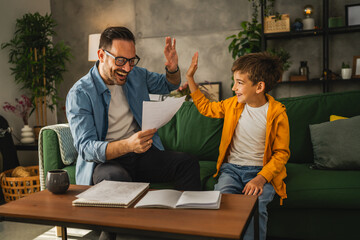 Happy and satisfied little boy show his father good grade on his test