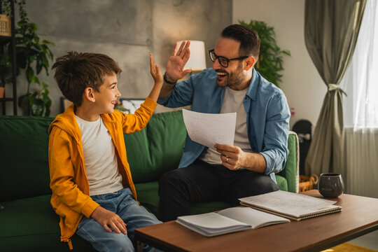 Happy and satisfied little boy show his father good grade on his test
