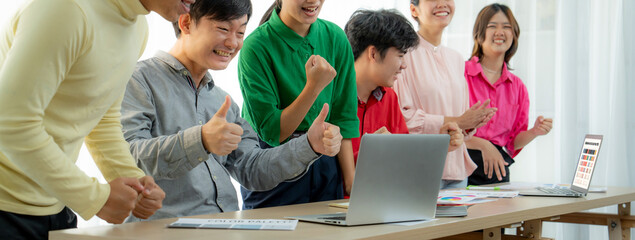Cropped image of Young creative business team celebrates successful business plan with laptop and...
