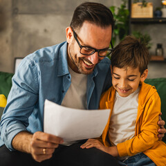 Happy and satisfied little boy show his father good grade on his test