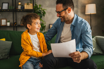 Happy and satisfied little boy show his father good grade on his test