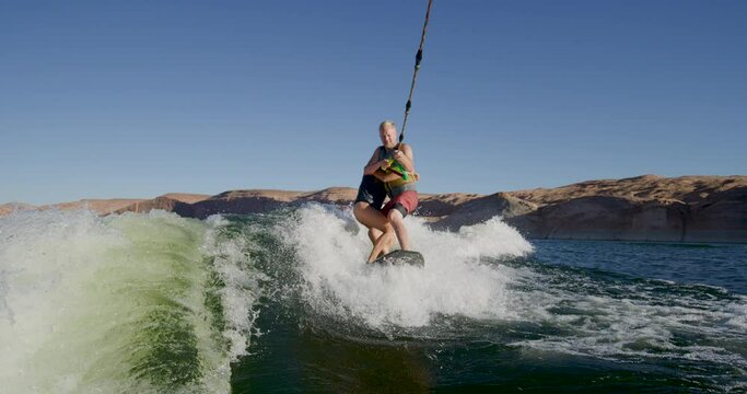 Man and woman wakeboarding on same board - slow motion