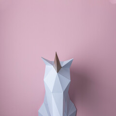 White 3d papercraft model of unicorn head on pink background. Minimal art concept.