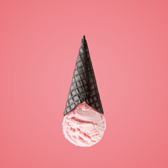 Ice cream scoop with upside down black ice cream cone on bright background. Minimal summer concept.