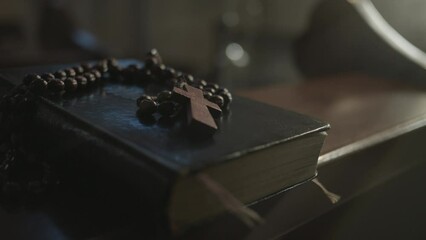 Holy Bible and prayer beads with cross in Christian church closeup. Psalmbook and rosary on wooden desk in temple closeup. Religious worship symbols concept