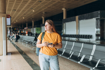 Happy Caucasian Woman waiting at Flight Gates for Plane Boarding, Uses Mobile Smartphone. 30s female Checking Trip Destination on Internet, concept of traveling