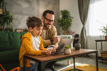 Father and son buy online with credit card on laptop at home