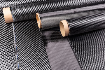 Rolls with various real woven carbon fiber enforcement raw material cloth. composite material automotive and car tuning  industry  high tech background.