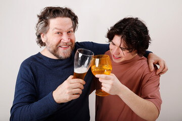 father and son in their twenties toasting with beer