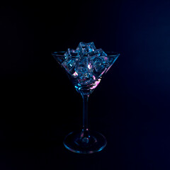 Martini glass with ice cubes in neon holographic vibrant pink and blue colors. Minimal celebration concept.
