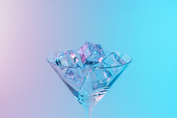 Martini glass with ice cubes in neon holographic vibrant pink and blue colors. Minimal celebration concept.