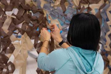 volunteers weave camouflage nets.