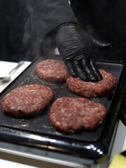 chef frying meat on the grill to make hamburgers